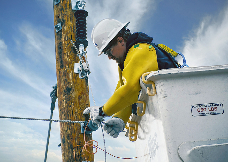 line worker in cherry picker working on electrical pole