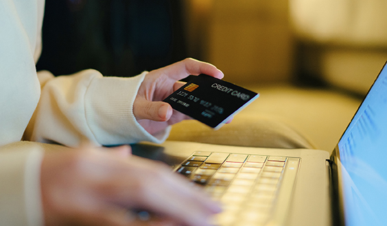 Hand holding credit card while on computer