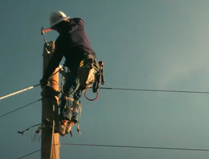 Line worker on top of electrical pole