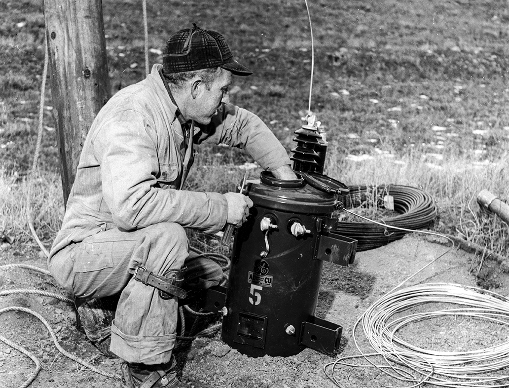 Black and white photo of lineman working on transformer