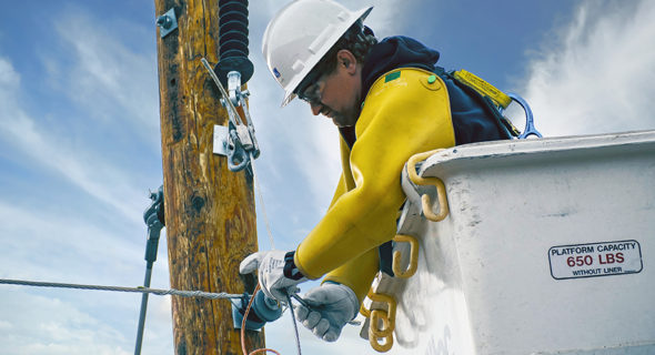 line worker in cherry picker working on electrical pole