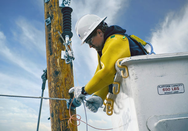 line worker in cherry picker working on electrical pole