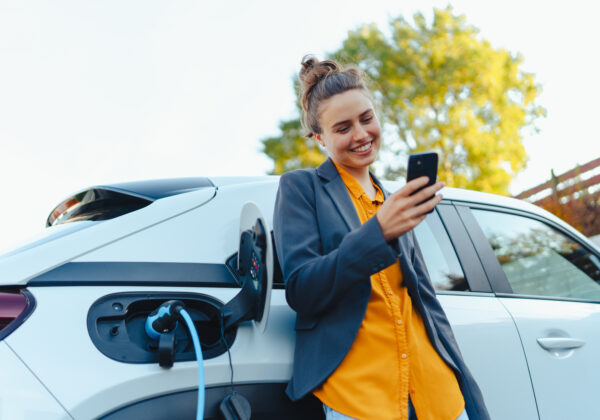 woman with phone charging EV